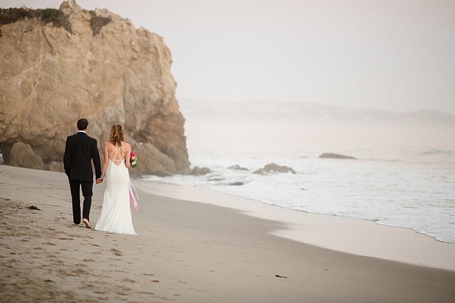 bride and groom walking into sunset on the beach