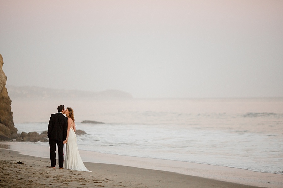 bride and groom kiss by the ocean at matador beach