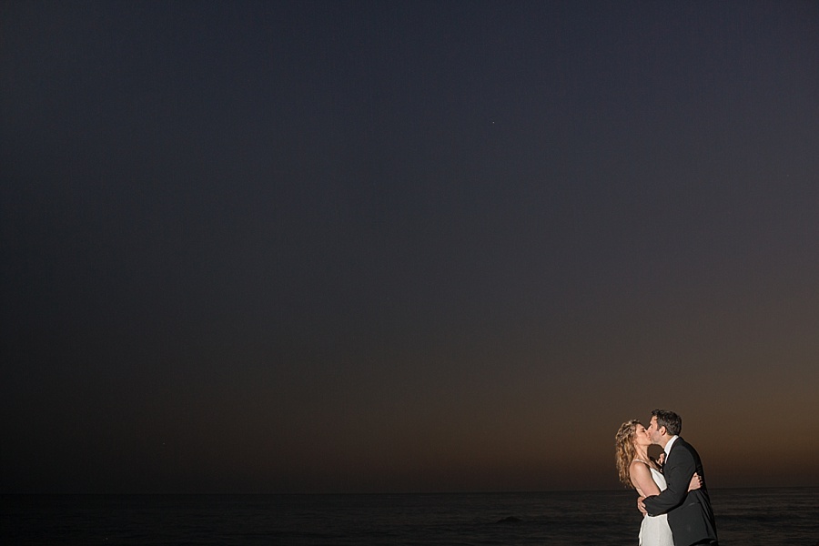 wedding couple kiss at beach at dusk in california