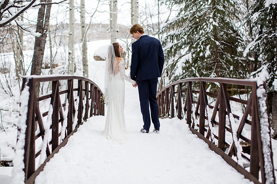 bride and groom walking in the snow on a bridge in beaver creek colorado