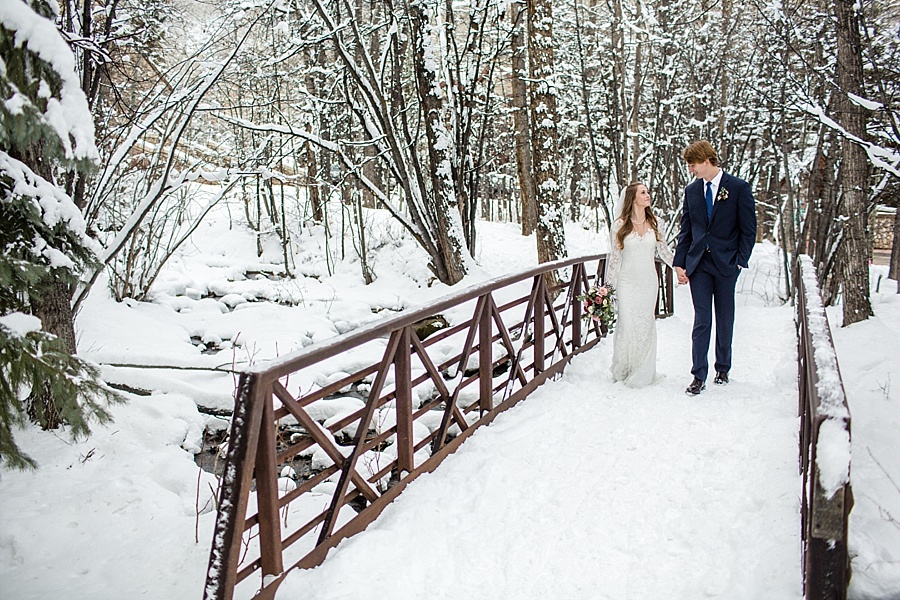 bride and groom looking at each other on a wooden bridge in the snow in beaver creek colorado