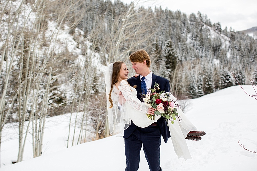 groom sweeps bride off her feet in the snow and carries her