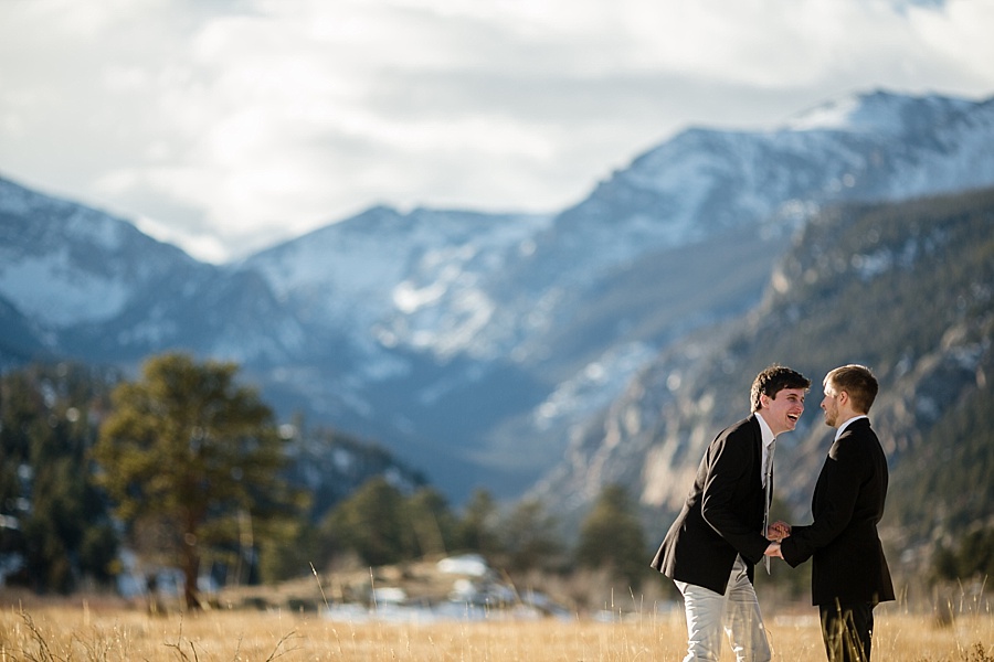 gay couple laughing with gorgeous colorado mountains behind them 