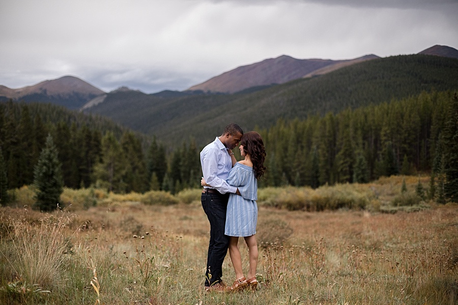 bride and groom to be hold each other with stunning mountain backdrop in colorado 