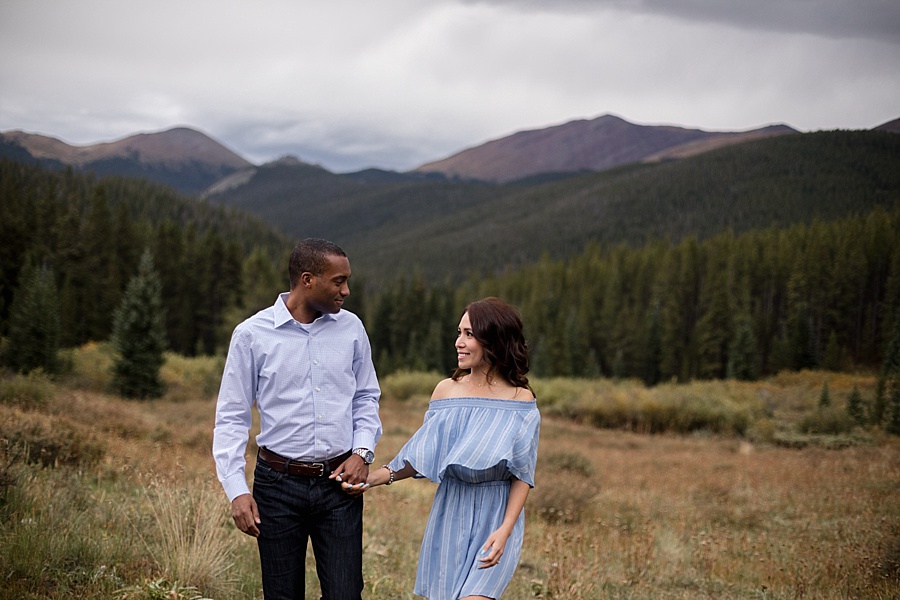 engaged biracial couple walking in the mountains of breckenridge 