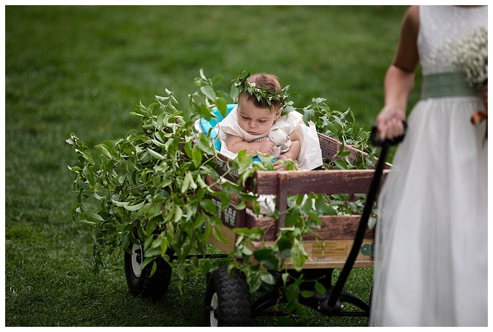baby flower girl with leaves and baby's breath in a wagon