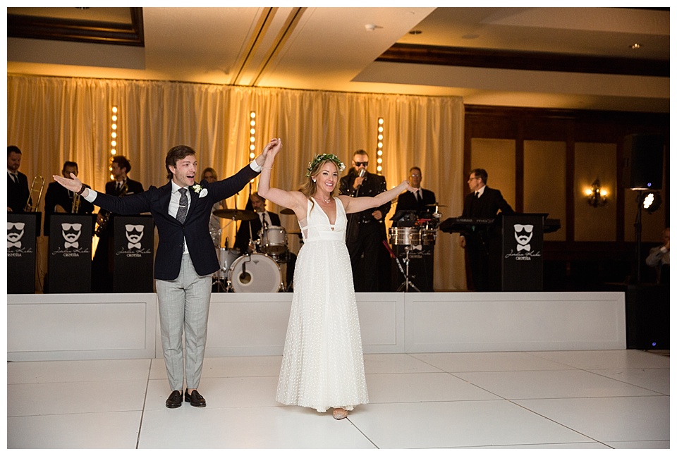 bride and groom cheer with their arms up at the end of their first dance 