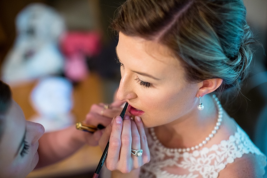 bride putting on lipstick on her wedding day in keystone colorado 