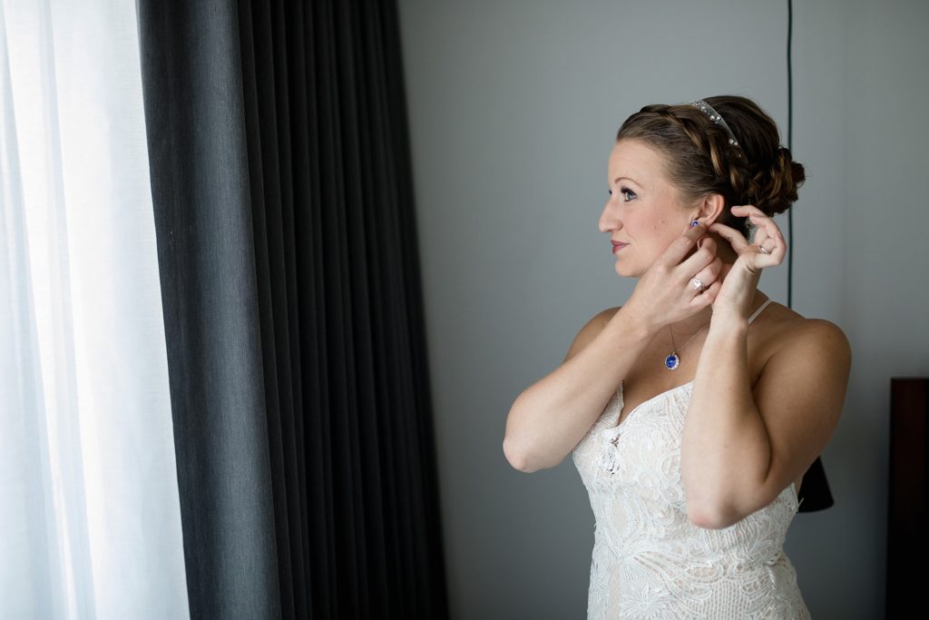 portrait of bride putting her earrings on at the maven