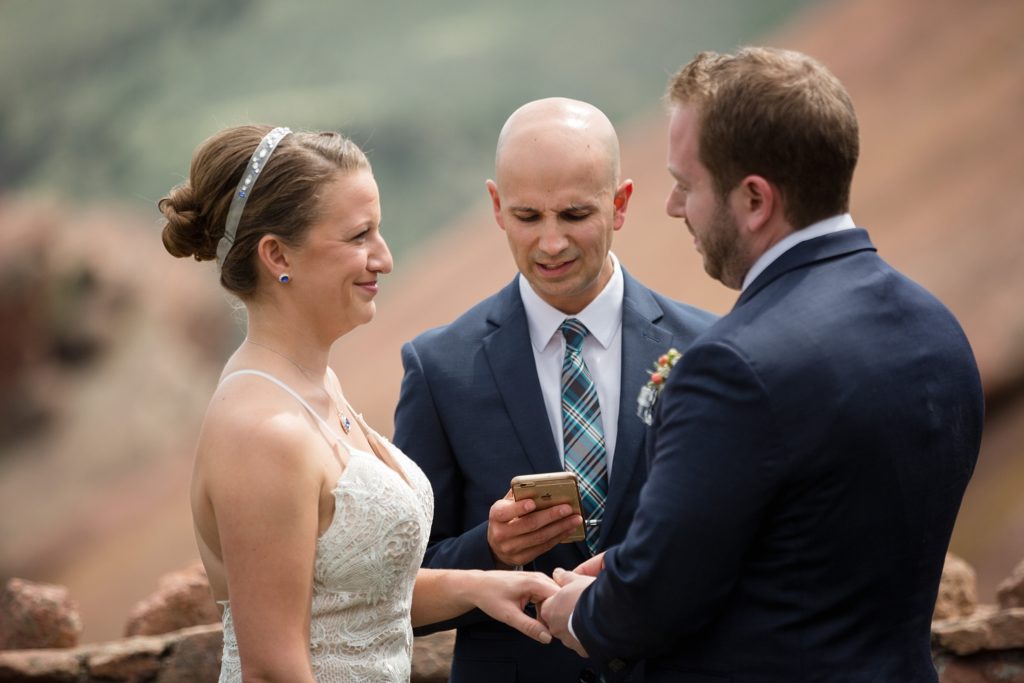 groom places ring on bride's finger at red rocks trading post 