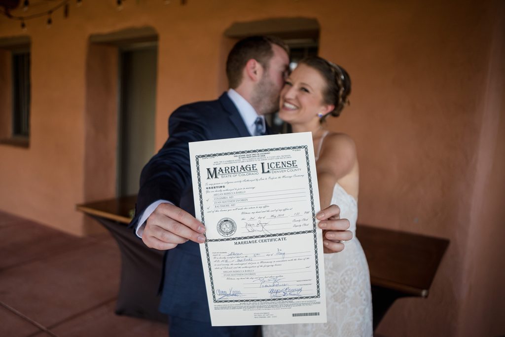 bride and groom hold colorado wedding lisence after tying the knot 