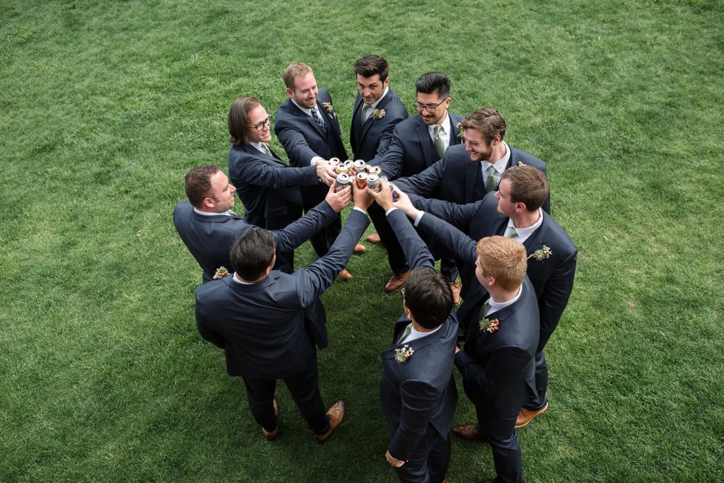 groomsmen and groom toast with beers after the wedding ceremony 