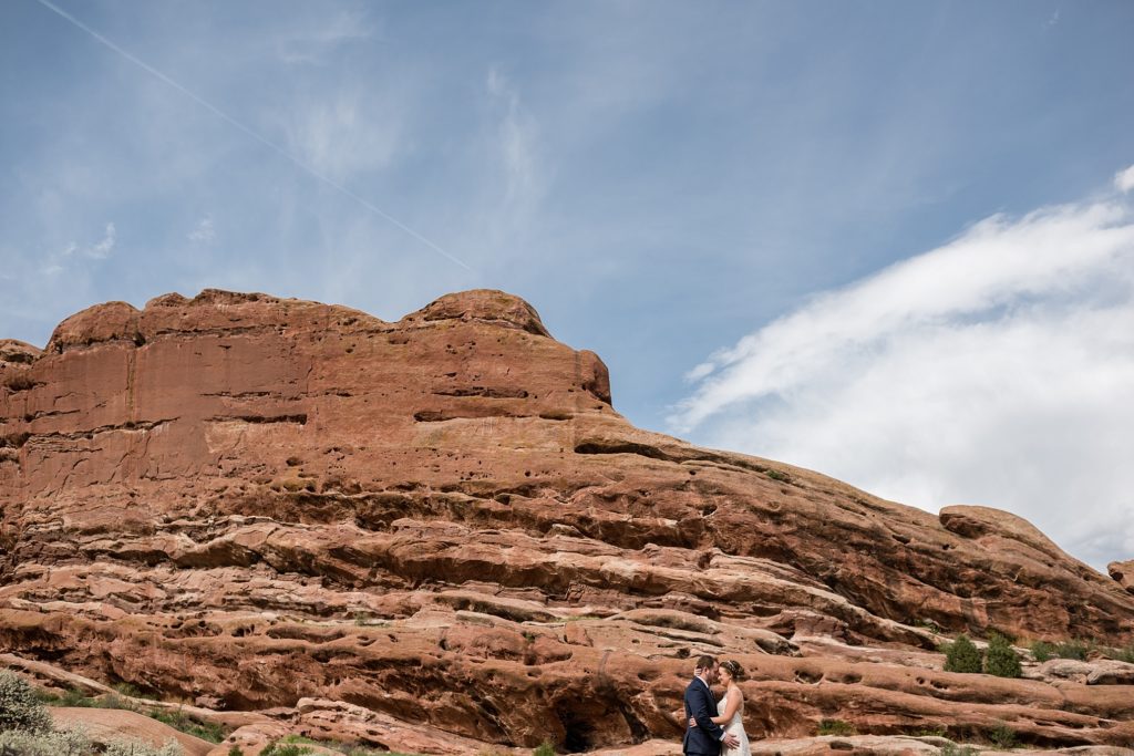 bride and groom hold each other in front of red rocks in colorado