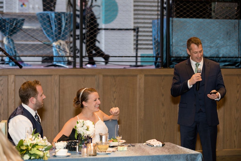bride and groom laugh during bride's father's toast at wedding reception 
