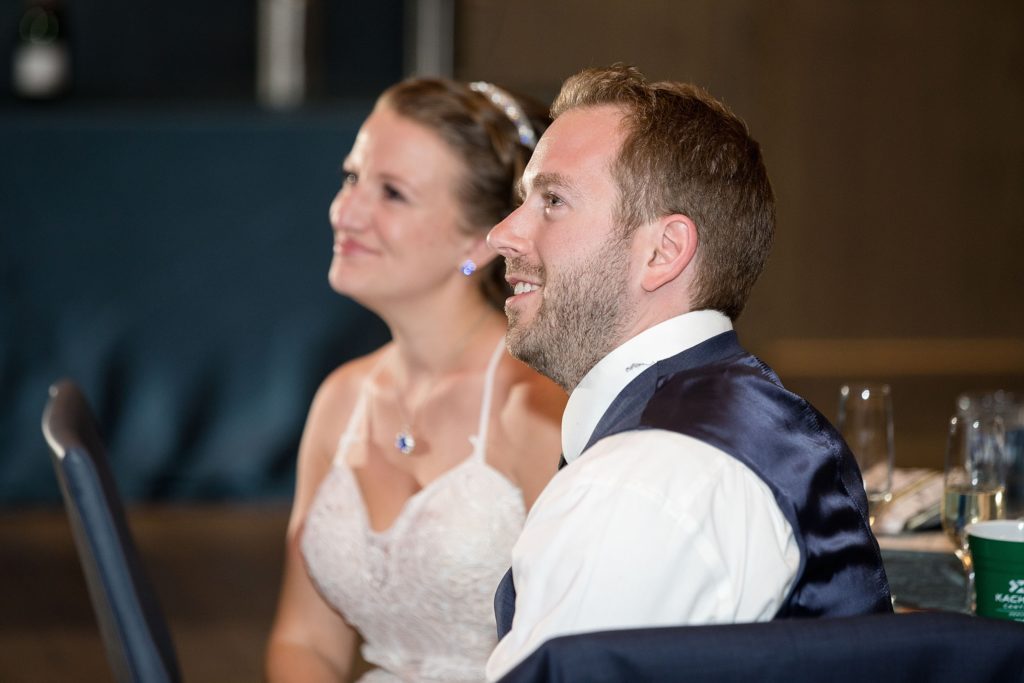 groom smiles during best man speech at his denver wedding