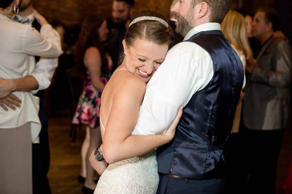bride hugs groom's arm during their wedding reception in downtown denver