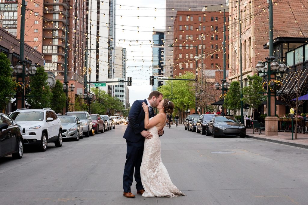 bride and groom kiss in larimer square in denver with string lights 