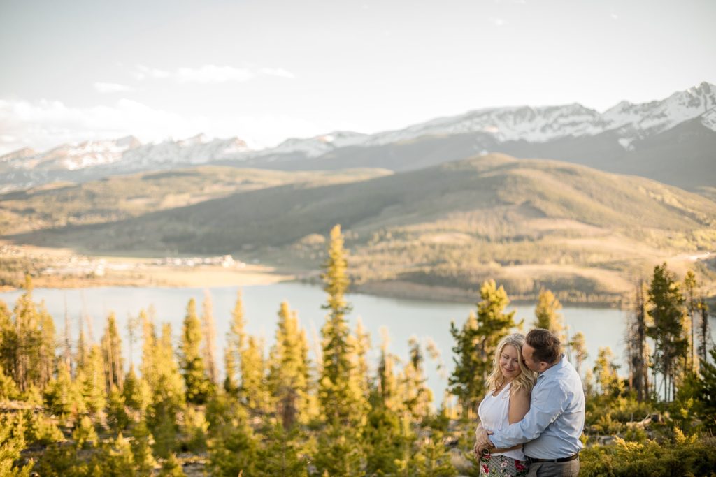 groom to be kisses bride to be in front of stunning backdrop