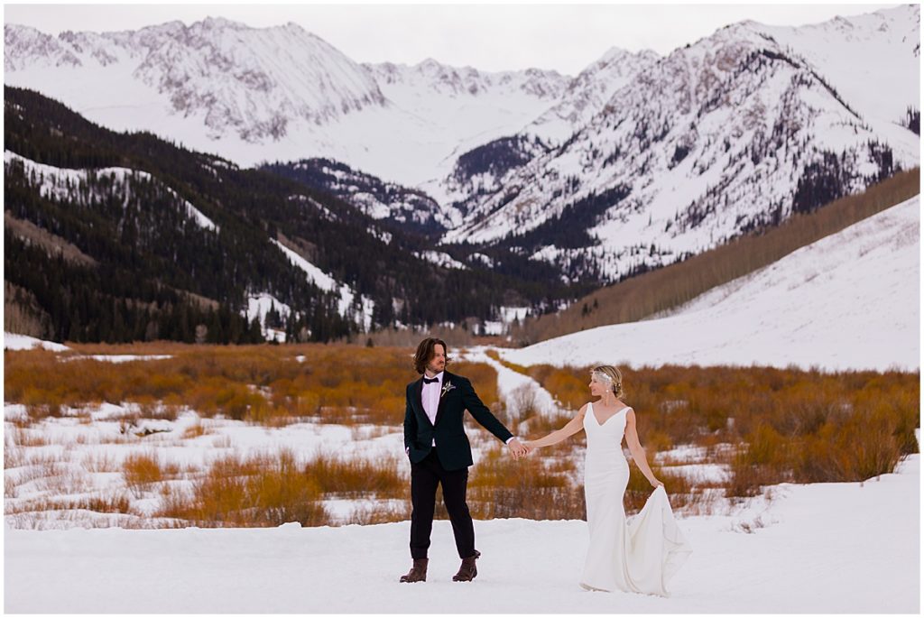 Bride and groom outside at The Pine Creek Cookhouse in the winter snow.  The bride is wearing a dress from Jenny Yoo holding bouquet designed by Aspen Branch Design.