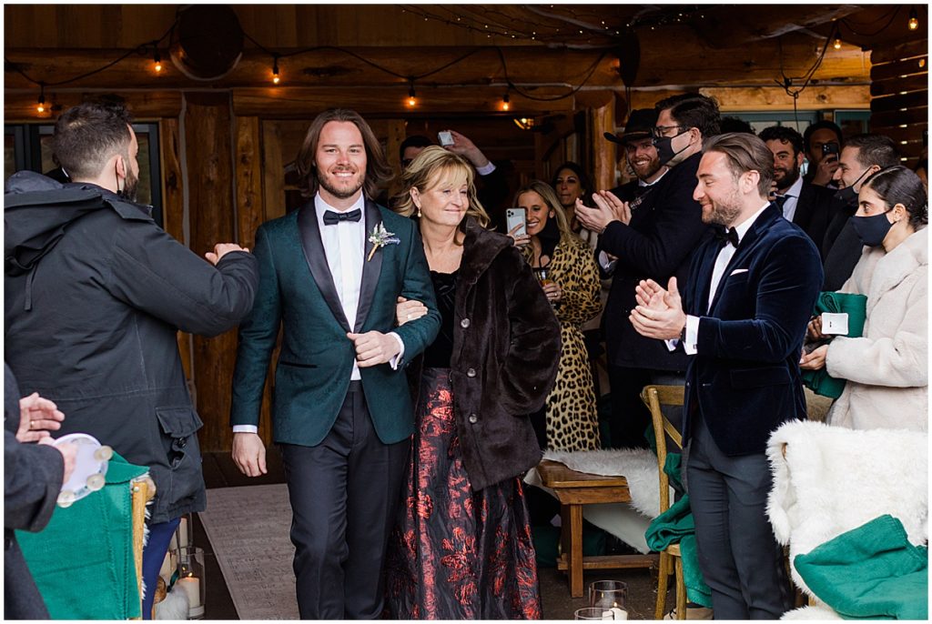 Groom and mom walking down the aisle for winter wedding at The Pine Creek Cookhouse in Aspen.