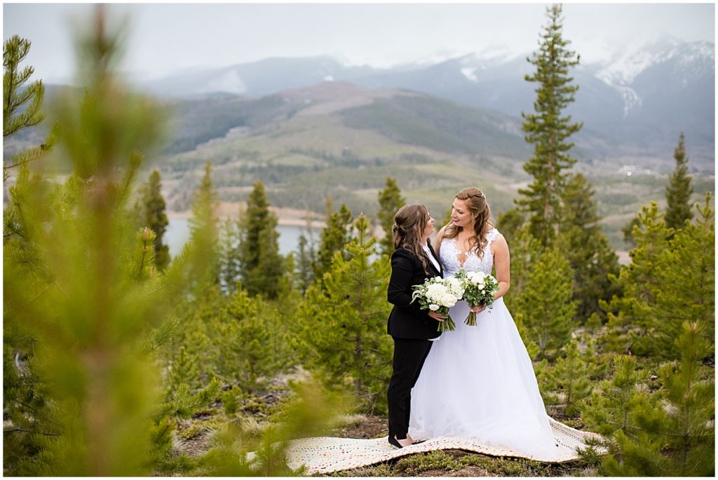 Bride outside holding bouquets designed by Indigo Flowers before elopement ceremony at Sapphire Point in Breckenridge.