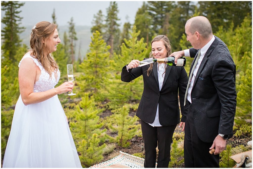 Brides celebrating with champagne  during LGBTQ elopement ceremony at Sapphire Point in Breckenridge.