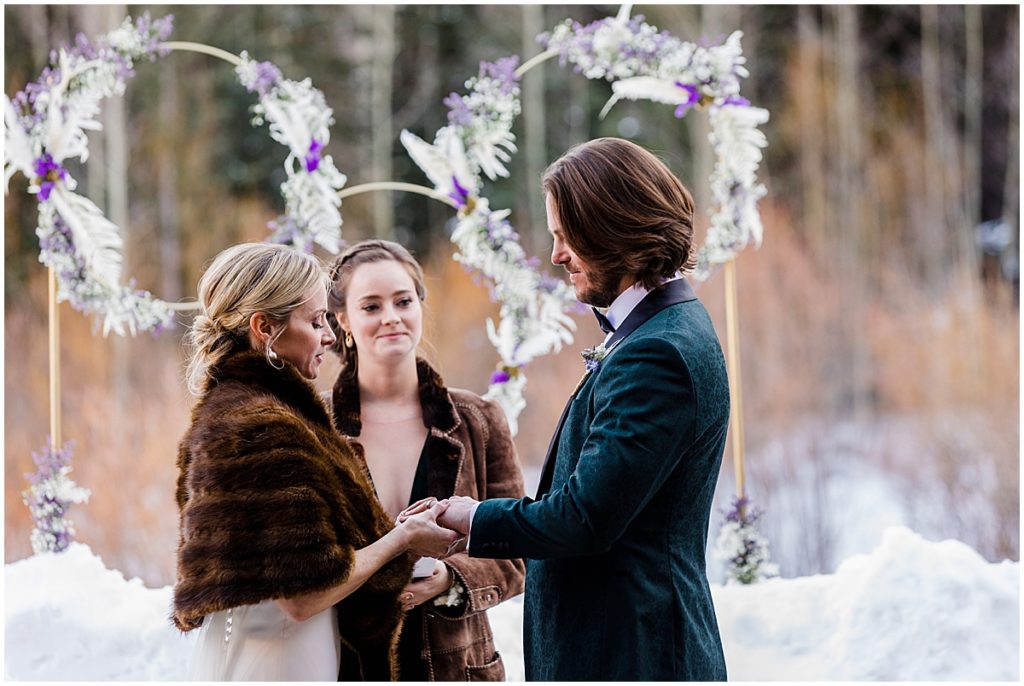 Bride and groom exchanging rings during winter wedding at The Pine Creek Cookhouse in Aspen