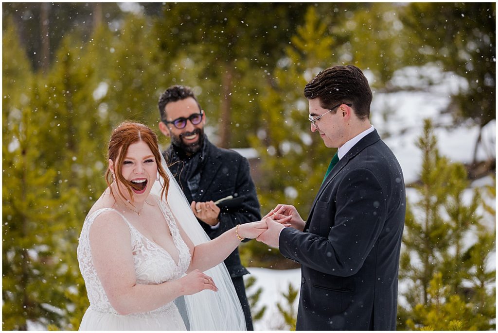 Bride and groom exchanging wedding rings at Sapphire Point in Breckenridge for a micro wedding ceremony.  Bride is wearing a dress from Champagne and Lace Bridal.