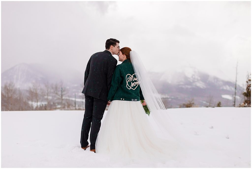 Bride and groom at Sapphire Point in Breckenridge during winter micro wedding ceremony.  Bride is wearing a dress from Champagne and Lace Bridal. 