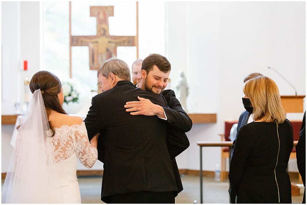 Groom hugging father of the bride at Vail Chapel during wedding ceremony.