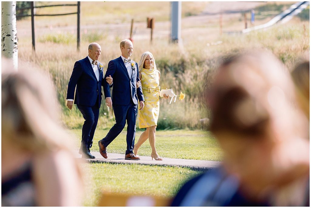 Groom wearing suit from Indochino walking down for wedding ceremony at Larkspur Vail.