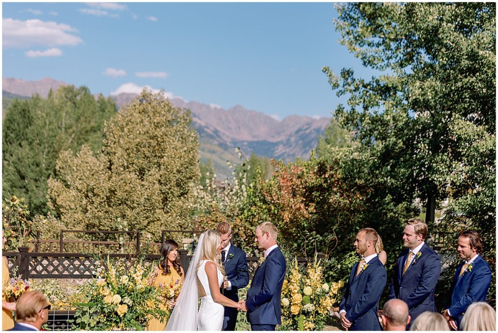 Bride and groom during ceremony at Larkspur Vail.  Floral decor by CVB Studio.  Bride is wearing dress from Annika Bridal and groom wearing suit from The Suit Shop.