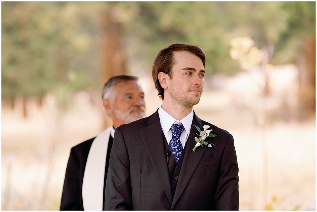 Groom Wearing suit from Men's Wearhouse watching bride come down aisle.
