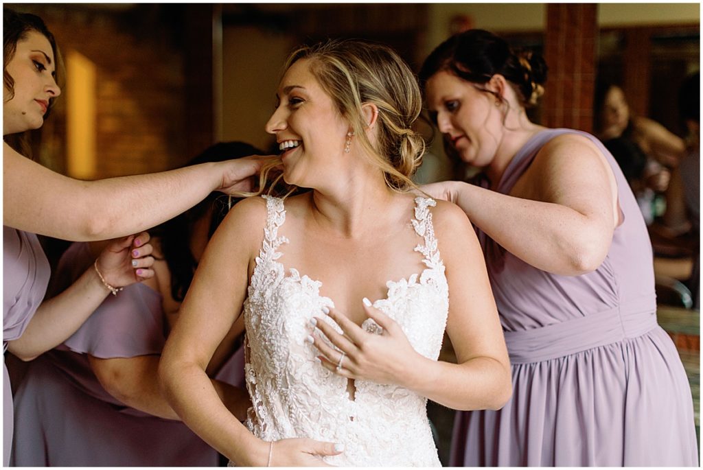 Bride putting on wedding dress designed by Martina Liana from Volle's Bridal & Boutique at Della Terra Mountain Chateau in Estes Park.