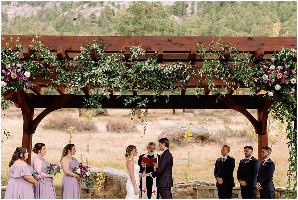 Wedding at Della Terra Mountain Chateau in Estes Park.  Bride wearing wedding dress designed by Martina Liana from Volle's Bridal & Boutique.  Groom Wearing suit from Men's Wearhouse.  Arch floral design by The Perfect Petal.
