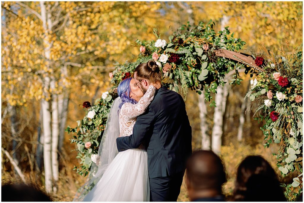 Bride and groom kiss during wedding ceremony at Anderson's Cabin in Beaver Creek.
