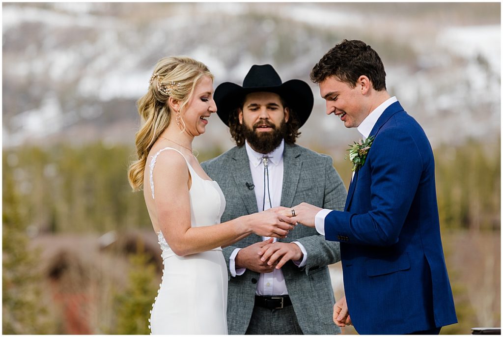 Bride putting ring on groom's finger during ceremony at Devil's Thumb Ranch.