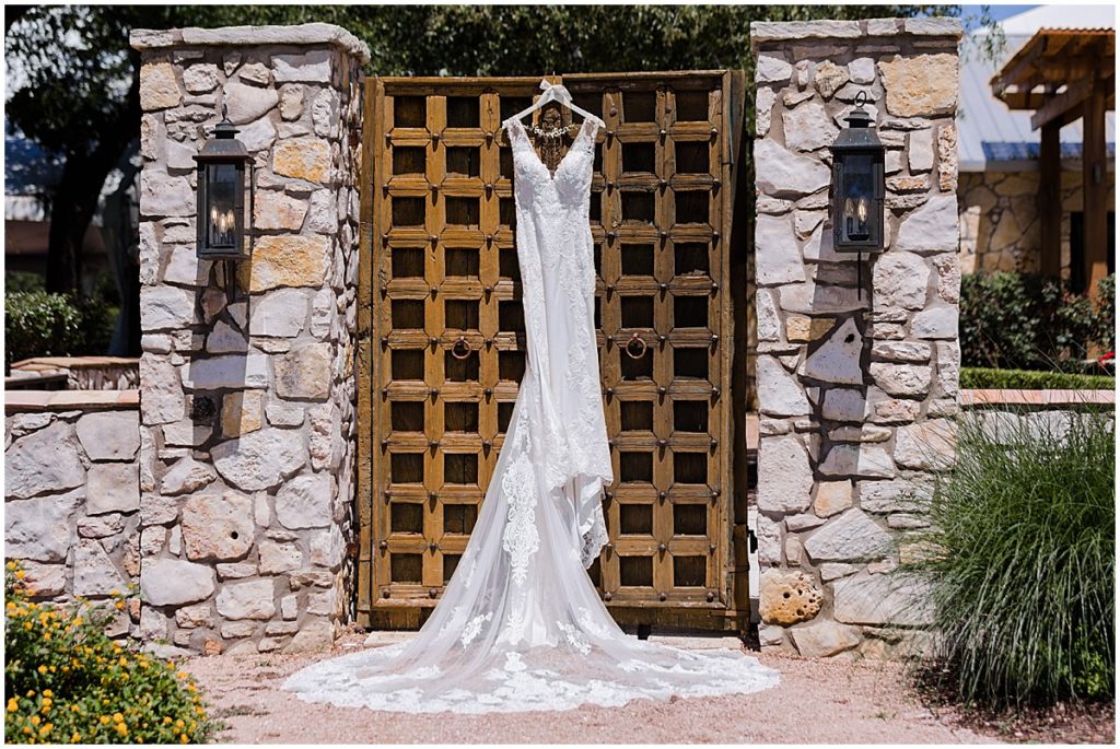 Brides wedding dress hanging at the gate of The Vineyards and Chappel Lodge in Austin Texas.