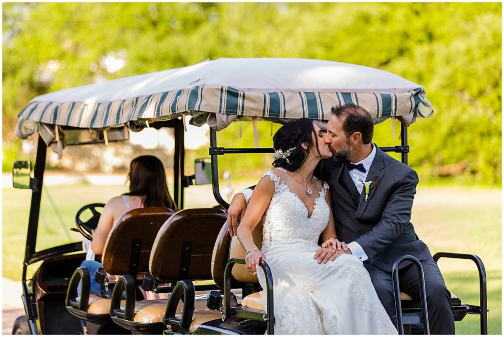 Bride and groom sitting on back of golf cart at The Vineyards at Chappel Lodge.  Bride wearing dress from Alexia Gavela Bridal and groom wearing suit from Men's Wearhouse.  