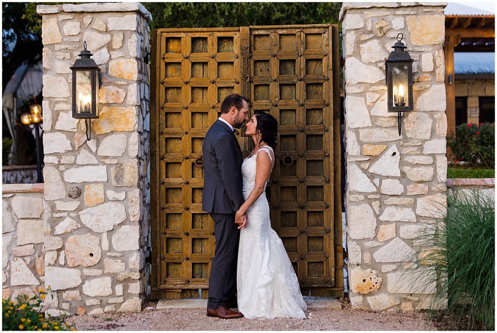 Bride and groom outside entrance doors at The Vineyards at Chappel Lodge.  Bride wearing dress from Alexia Gavela Bridal and groom wearing suit from Men's Wearhouse.  