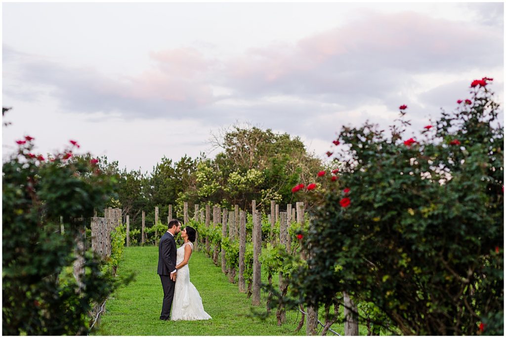 Bride and groom walking outside in the gardens at The Vineyards at Chappel Lodge.  Bride wearing dress from Alexia Gavela Bridal and groom wearing suit from Men's Wearhouse.  