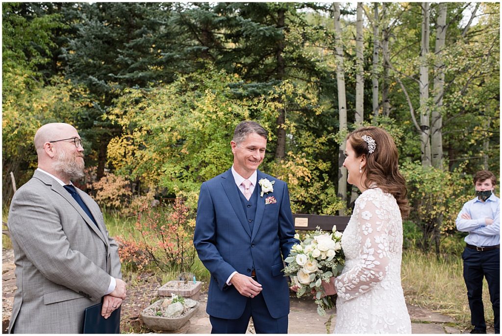 Bride and groom holding hands next to officiant at Betty Ford Alpine Gardens in Vail for micro wedding.  