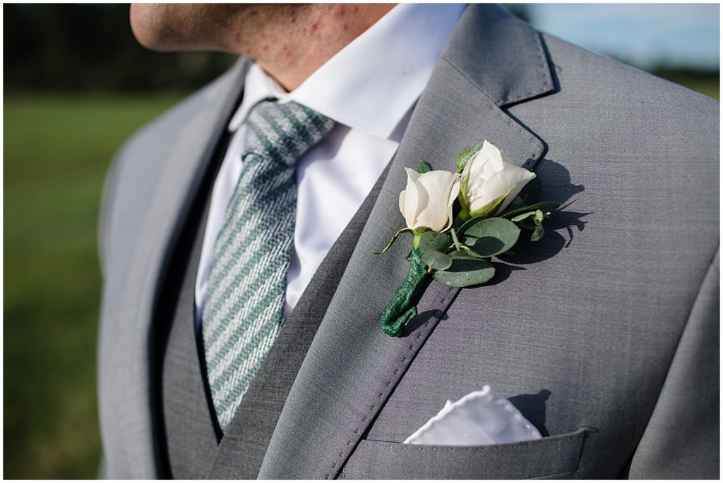 Groom wearing boutonniere  at Three Sisters Park in Evergreen
