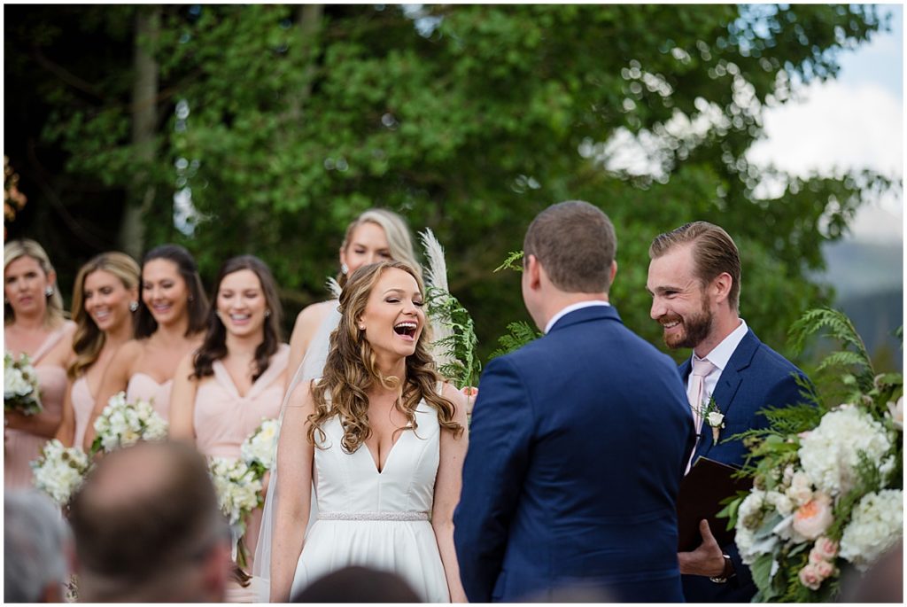 Bride laughing with groom outside during wedding ceremony at 10 mile station in Breckenridge