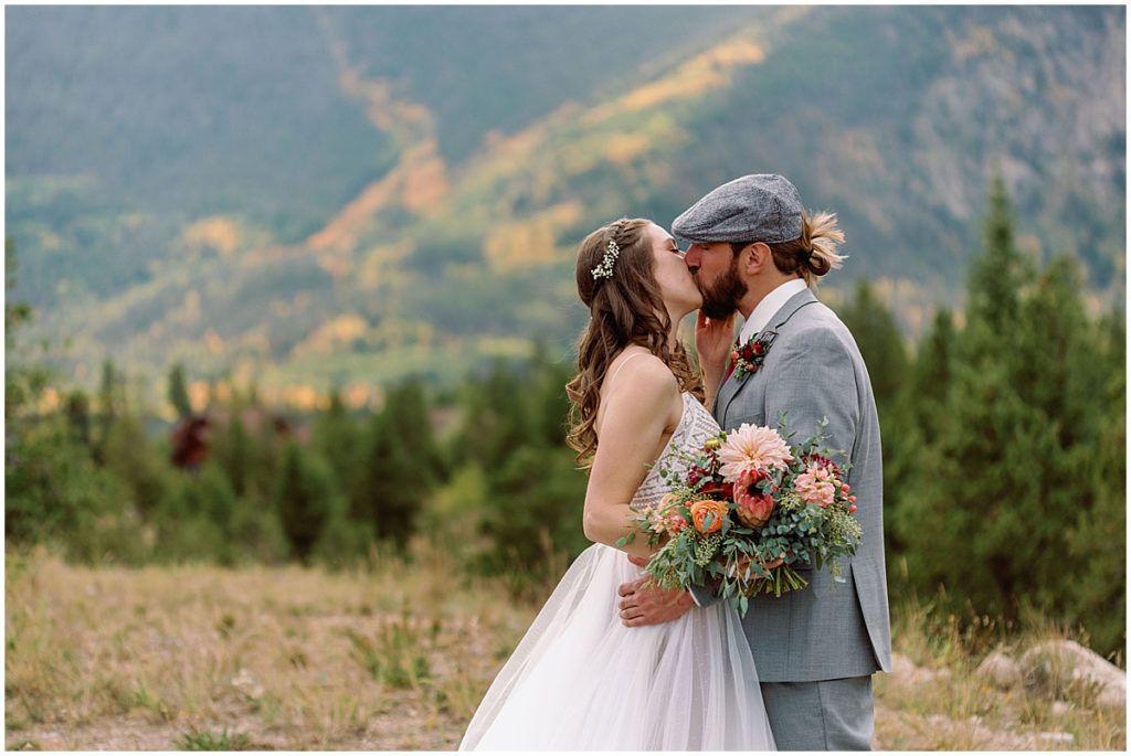 Bride and groom kiss during first look at Frisco Day Lodge.   Bride is wearing dress from A&BE Bridal Shop and groom wearing suit from Jim's Formal Wear.  Bride's bouquet designed by Garden of Eden Flowers and Gifts. 