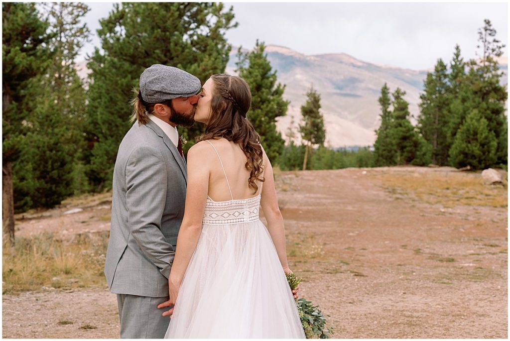 Bride and groom kissing at Frisco Day Lodge.  Bride is wearing dress from A&BE Bridal Shop and groom wearing suit from Jim's Formal Wear.