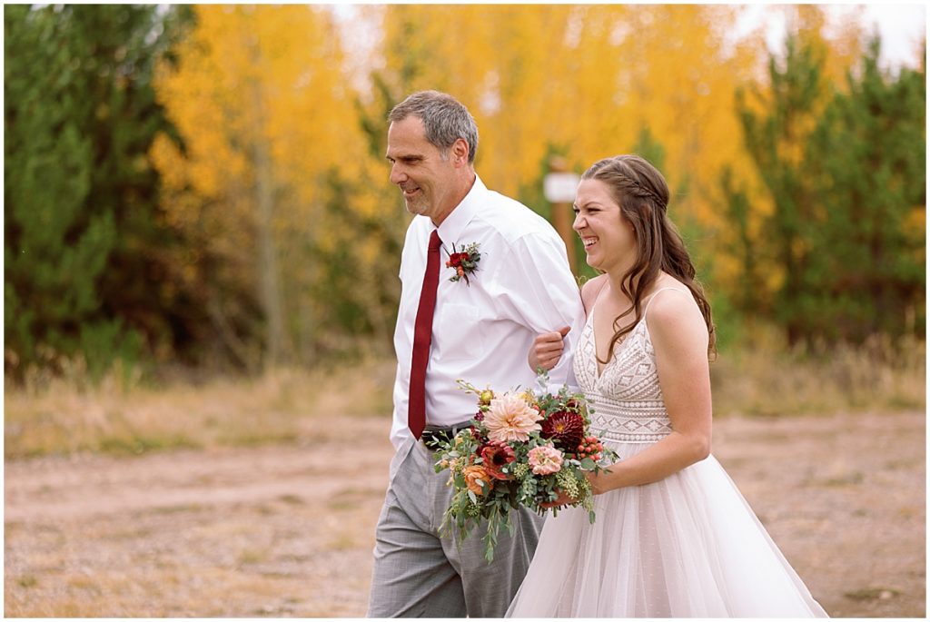 Father and bride walking down for wedding at Frisco Day Lodge.  Bride is wearing dress from A&BE Bridal Shop.  Bride's bouquet designed by Garden of Eden Flowers and Gifts. 