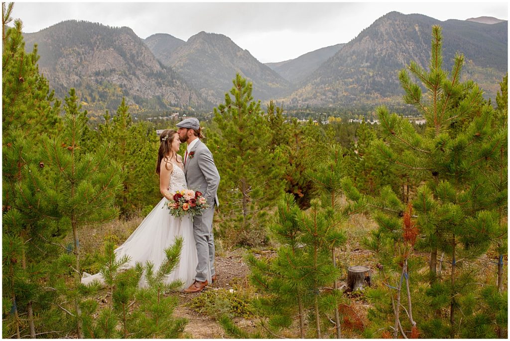 Bride and groom in pine tree forest after wedding ceremony at Frisco Day Lodge  Bride is wearing dress from A&BE Bridal Shop and groom wearing suit from Jim's Formal Wear.  Bride's bouquet designed by Garden of Eden Flowers and Gifts. 