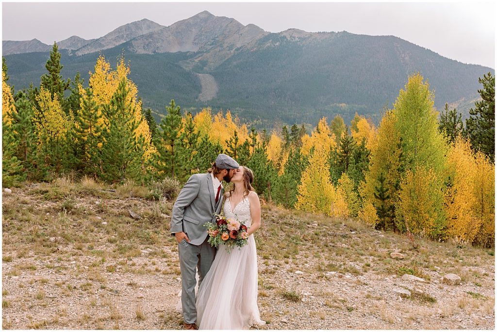 Bride and groom walking through aspen trees after wedding ceremony at Frisco Day Lodge  Bride is wearing dress from A&BE Bridal Shop and groom wearing suit from Jim's Formal Wear.  Bride's bouquet designed by Garden of Eden Flowers and Gifts. 