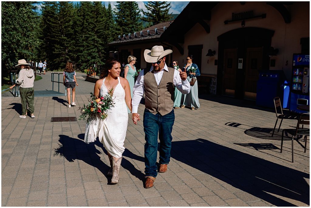 Bride and groom walking to gondola for wedding at The Holy Cross Overlook in Vail.  Bride holding bouquet from Garden of Eden.